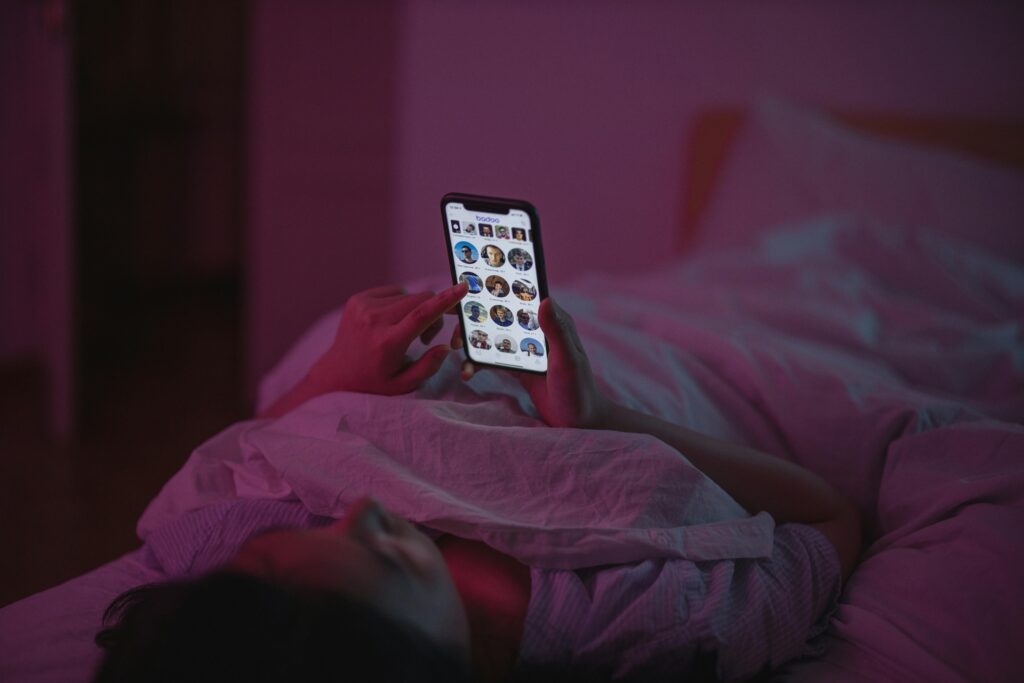 Person nutzt das Handy im Bett und verzögert absichtlich das Schlafengehen (Revenge Bedtime Procrastination)